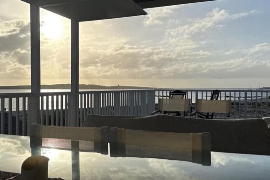 Tavolo di vetro con candele davanti alla terrazza e al mare al tramonto, Case Bianche